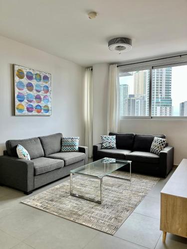 a living room with two couches and a glass table at Signature Point Bella Vista, Sea View 2 BR in Panama City