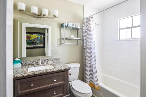 a bathroom with a sink and a toilet and a mirror at The Collins on Duval in Key West