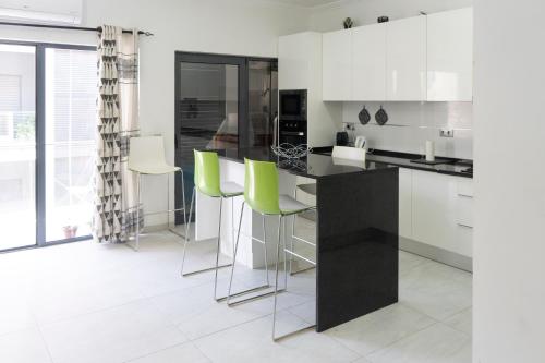 a kitchen with white cabinets and green bar stools at Charming 2 bdr apt, Palmarejo Grande, Praia - LCGR in Praia