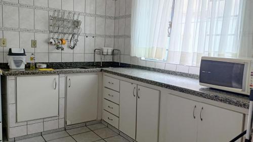 a kitchen with white cabinets and a microwave at CASA de 2 QUARTOS in Guaratinguetá