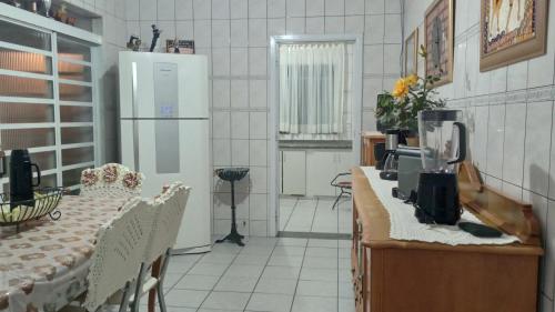 a kitchen with a table and a white refrigerator at CASA de 2 QUARTOS in Guaratinguetá