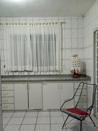 a kitchen with a chair and a cake on a counter at CASA de 2 QUARTOS in Guaratinguetá