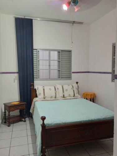 a bedroom with a large bed with a blue blanket at CASA de 2 QUARTOS in Guaratinguetá