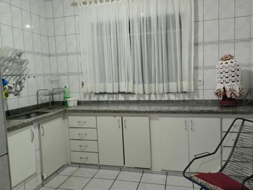 a kitchen with white cabinets and a sink and a window at CASA de 2 QUARTOS in Guaratinguetá