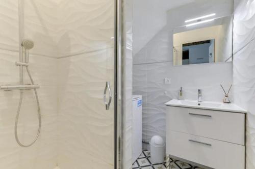 een witte badkamer met een douche en een wastafel bij Maison 3 Calme Charme Centre in Béziers