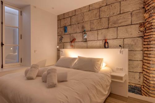 a bedroom with a white bed with a brick wall at L'Ardoise, L'Anjou, La Vigne et La Loire in Angers