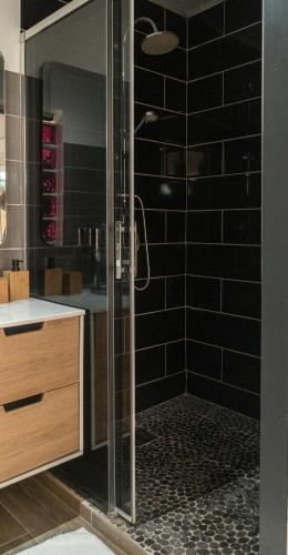 a bathroom with a shower with black tiles at Studio : Écaille de tortue in Sainte-Luce
