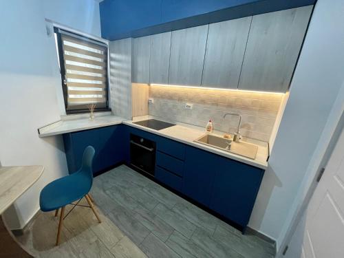 a small kitchen with a sink and a blue chair at Iulius Mall River Tower in Iaşi