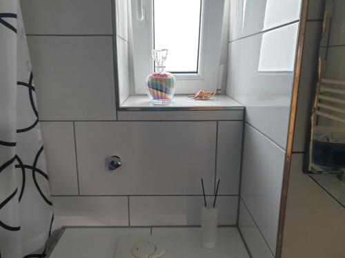 ein Badezimmer mit einem Fenster und einer Vase auf einem Fensterbrett in der Unterkunft Apartment in Mönchengladbach