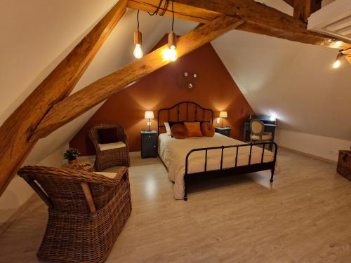 a bedroom with a bed and a chair in a attic at La Maison Pas'Chaaxe in Onzain