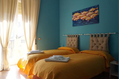 two beds in a room with blue walls at QuiSiSana a mare in Castellammare di Stabia