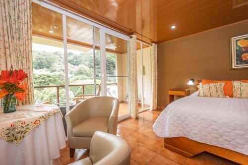 a bedroom with a bed and a chair and a window at El Oasis Hotel y Restaurante in Boquete