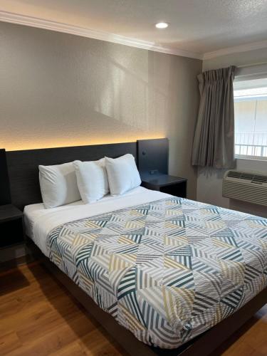 a bedroom with a bed with a comforter and a window at Motel 6 Sacramento, Ca - Downtown in Sacramento