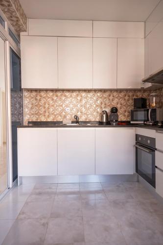 a kitchen with white cabinets and a tile floor at 3 bdr cozy apt in Condominio Mi, Palmarejo Grande in Praia