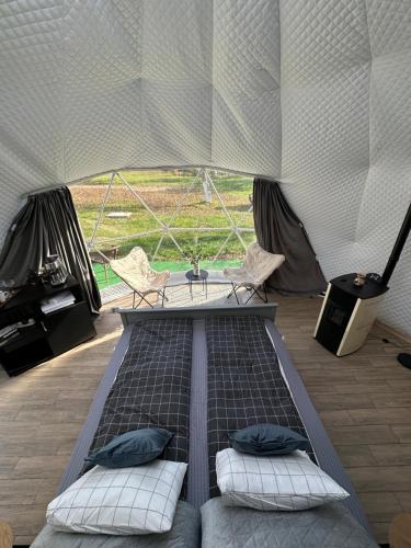 a bed in a tent with two chairs and a table at The Frog Glamping in Horezu