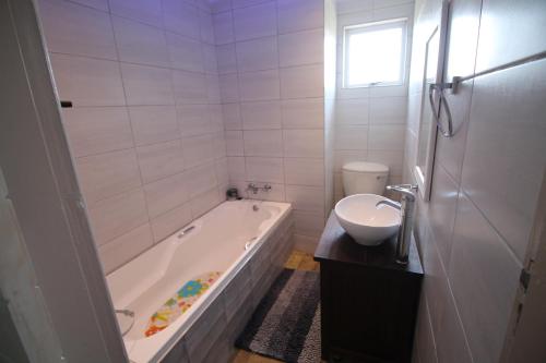 a white bathroom with a tub and a sink at Du Bantry 14 in Uvongo Beach