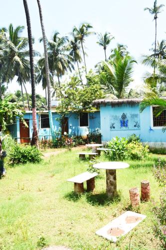 ein blaues Haus mit zwei Picknicktischen und Palmen in der Unterkunft Caasa De Nirvana by OceanSide 4 Guest in Velha Goa