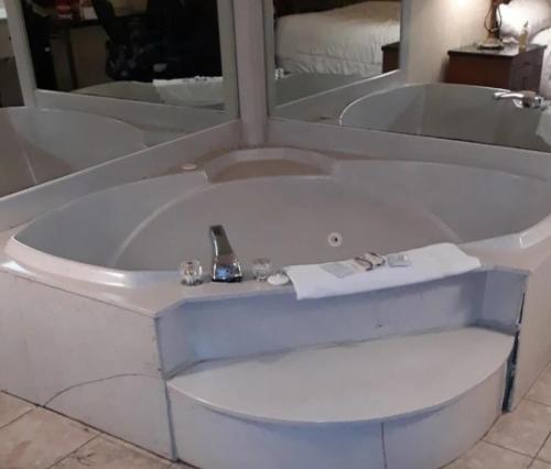 a white bath tub in a room with a mirror at Victory Suites in Warren