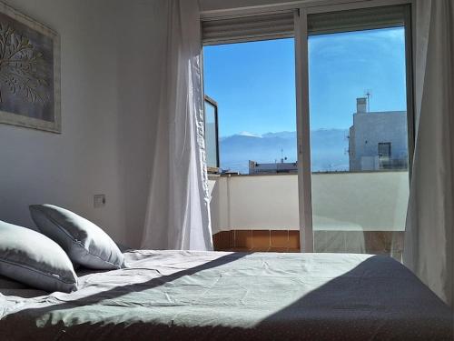 ein Schlafzimmer mit einem Bett und einem großen Fenster in der Unterkunft Ático de Laura in Armilla