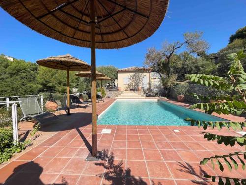 une piscine avec deux parasols à côté d'une piscine dans l'établissement Villa piscine vue sur mer Ollioules, à Ollioules