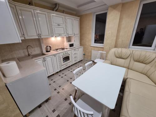 eine Küche und ein Wohnzimmer mit weißen Schränken und einem Tisch in der Unterkunft 1 bedroom and living, Testemiteanu str. in Chişinău