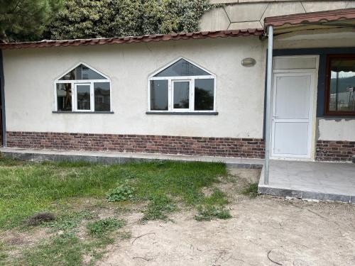 Una casa de ladrillo con dos ventanas y una puerta blanca en Batuhan tesisleri, en Çiftlikköy