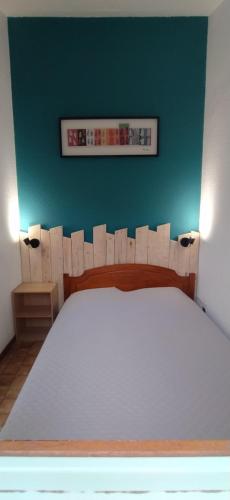 une chambre avec un lit blanc avec un mur vert dans l'établissement maison Valras Plage - Résidence Lou Portalou, à Valras-Plage