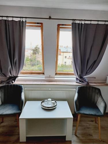 two chairs and a table in front of two windows at Piccola Italia Casa Racovita in Cluj-Napoca