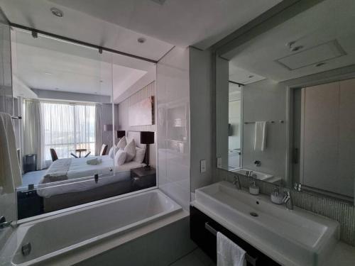 ヨハネスブルグにあるSandton Skye - luxury apartmentのバスルーム(ベッド1台、バスタブ、鏡付)