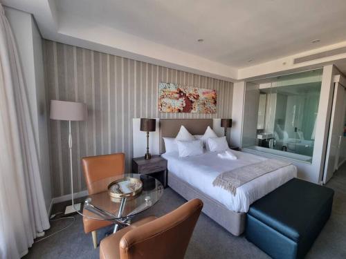 ヨハネスブルグにあるSandton Skye - luxury apartmentの大きなベッドとテーブルが備わるホテルルームです。