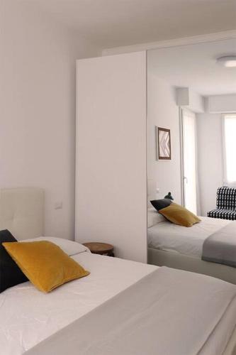 1 dormitorio blanco con 2 camas y almohadas amarillas en Appartamento Lorenteggio - Piazza Frattini affaccio interno, 2 balconi, en Milán