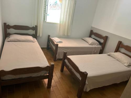a room with three beds and a window at Nosso Recanto Pérola in Capitólio