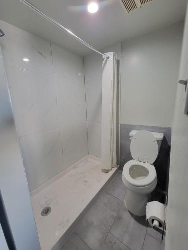 a white bathroom with a toilet and a shower at Maxim III Motel in Houston