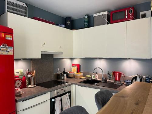 a kitchen with white cabinets and a red refrigerator at Appartement, piscine, Garches in Garches