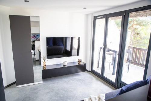 uma sala de estar com televisão e uma grande janela em Bienvenue dans le cobalt ! em Cholonge