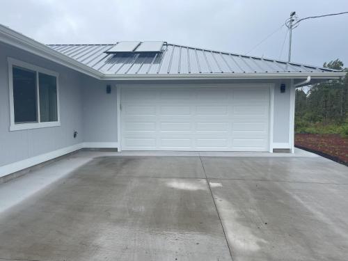 a white garage with a door and a roof at Orchid Land in Keaau