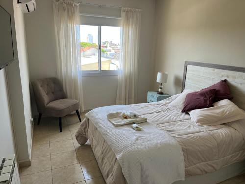 ein Schlafzimmer mit einem Bett mit einem Stuhl und einem Fenster in der Unterkunft DEPARTAMENTO CENTRICO in Dolores