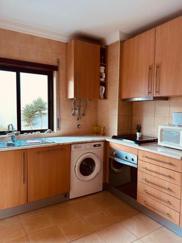 a kitchen with wooden cabinets and a washing machine at Apartment Salgados T1 in Guia