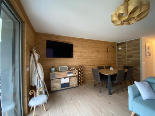 un salon avec une table et une télévision au mur dans l'établissement Appartement proche des pistes Serre Chevalier, à Briançon