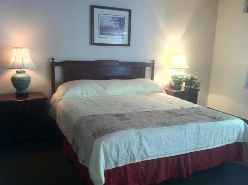 a bedroom with a large bed with two lamps at Caravelle Inn Extended Stay in San Jose