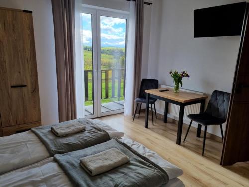 a living room with a bed and a table and a window at Dom na Ubocy in Groń