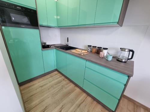 a kitchen with blue cabinets and a wooden floor at Dom na Ubocy in Groń