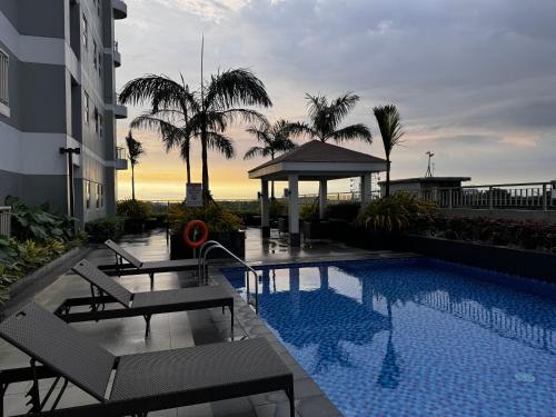 a pool with chairs and a gazebo next to a building at Beautiful 1bed condo Nr Airport, MOA, Makati, Bay in Manila