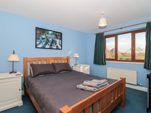 a bedroom with a bed with blue walls and windows at Morgan House in Bridgwater