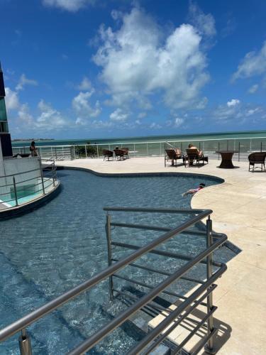 a pool of water with tables and a lighthouse at Apartamento beira mar in João Pessoa