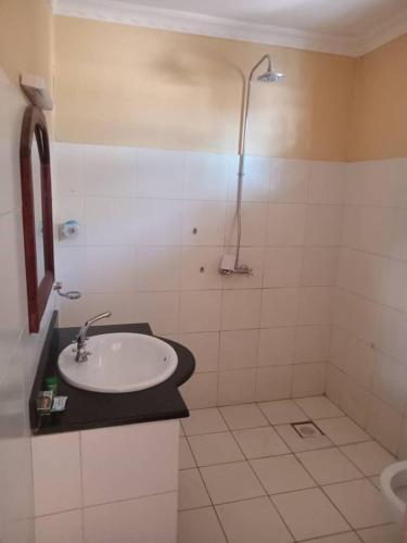 La salle de bains est pourvue d'un lavabo et d'une douche. dans l'établissement Makambo-te Makuti Cottage, à Arusha