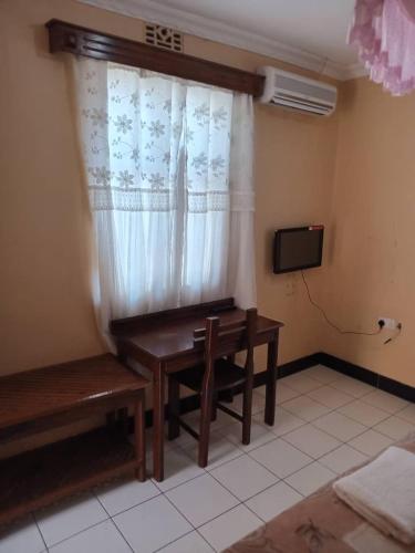 a room with a table and a window with a bench at Makambo-te Makuti Cottage in Arusha