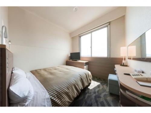 a bedroom with a bed and a desk with a computer at Onomichi Daiichi Hotel - Vacation STAY 02586v in Onomichi