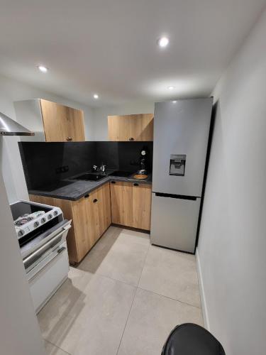 eine Küche mit einem weißen Kühlschrank und Holzschränken in der Unterkunft Studio 2 personnes équipé in Vignac