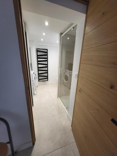 einen Flur mit einer Glastür, die zu einem Bad führt in der Unterkunft Studio 2 personnes équipé in Vignac